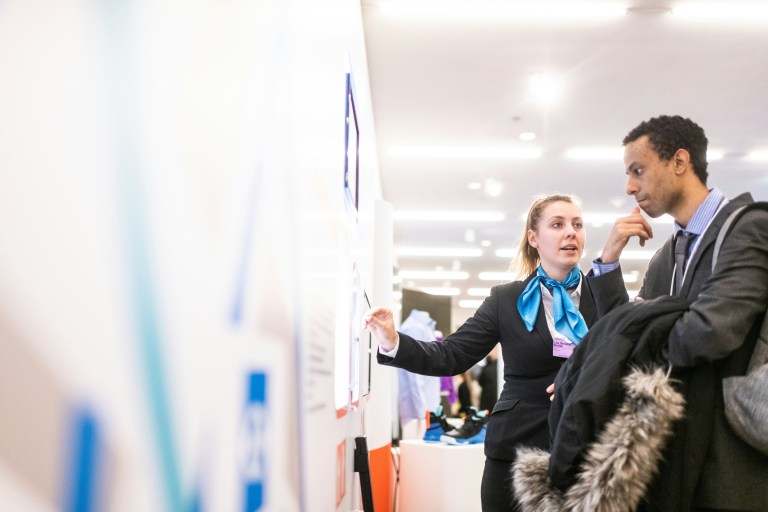 Two people looking at a job vacancies board, trying to find a job in 2024.