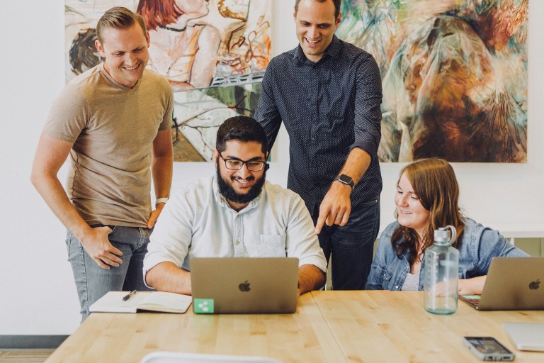 Happy employees in a modern office demonstrating strong employment practices and high employee morale.