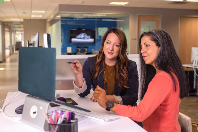 Two people sitting at a desk discussing AI in recruitment processes in a modern office setting.
