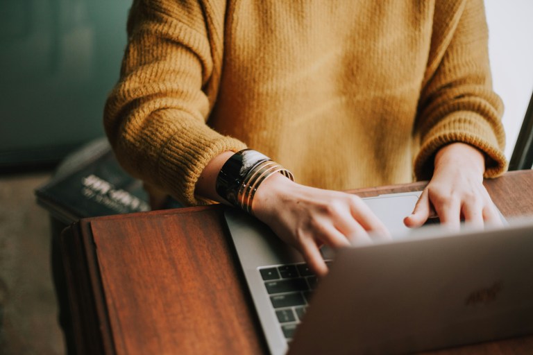 HR person looking for corporate HR solutions and hr software solutions on their laptop.