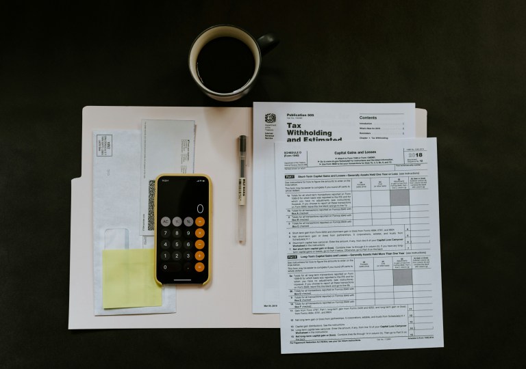 Tax documents and a calculator app on an iPhone, representing income tax, payroll tax and national insurance contribution in the Netherlands.
