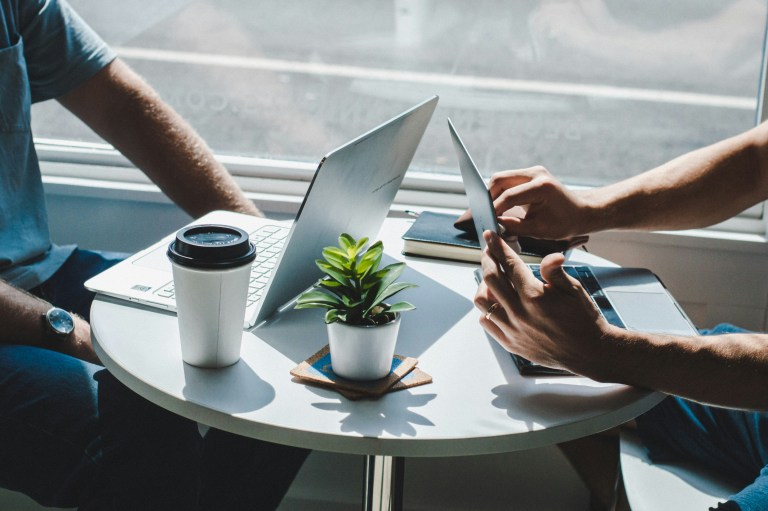 Two people working on laptops talking about how to expand your business to the Netherlands.